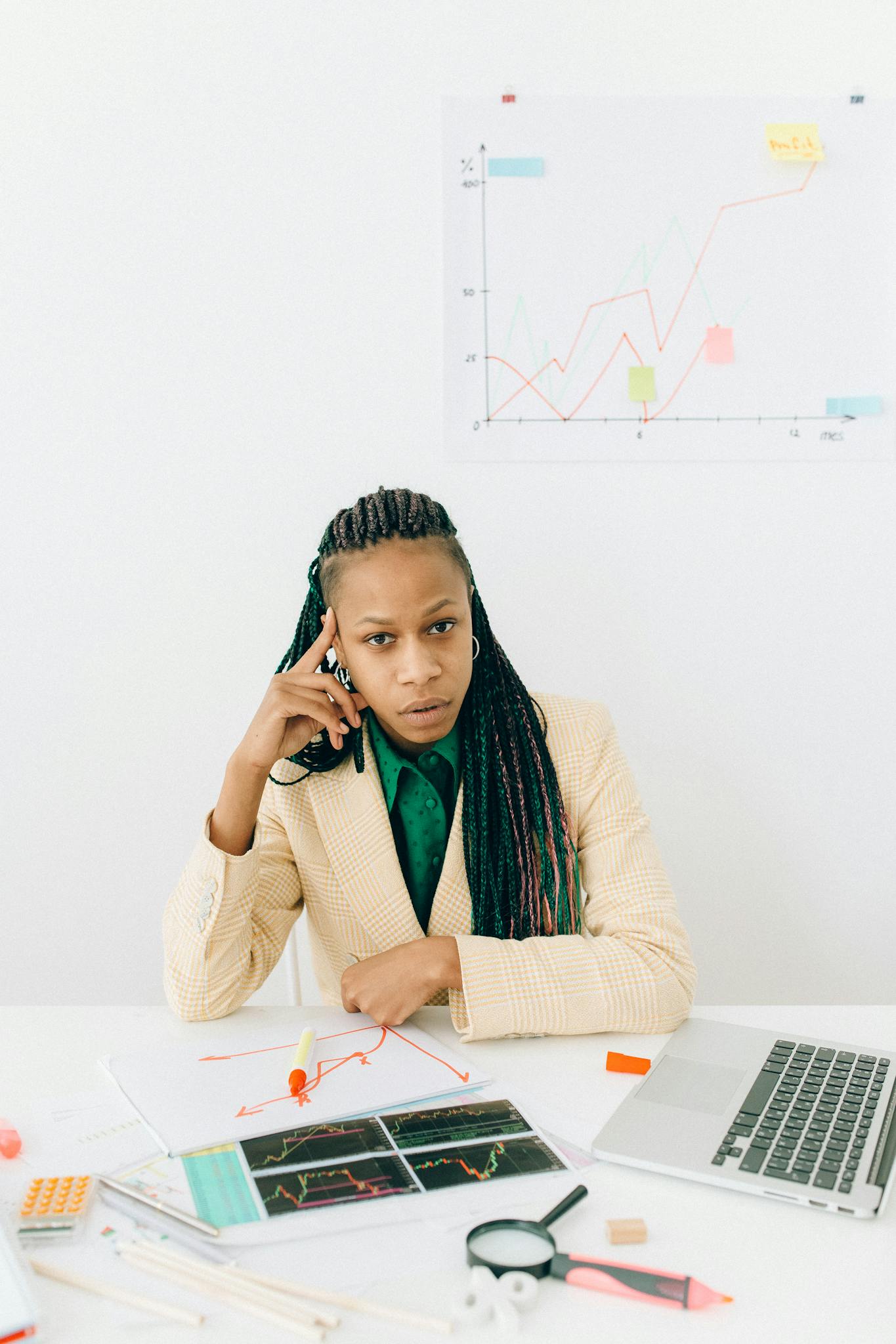 Professional woman analyzing financial graphs and data at an office desk, showcasing business expertise.